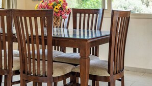 Un comedor con mesa y sillas de madera, una araña y una ventana con cortinas.