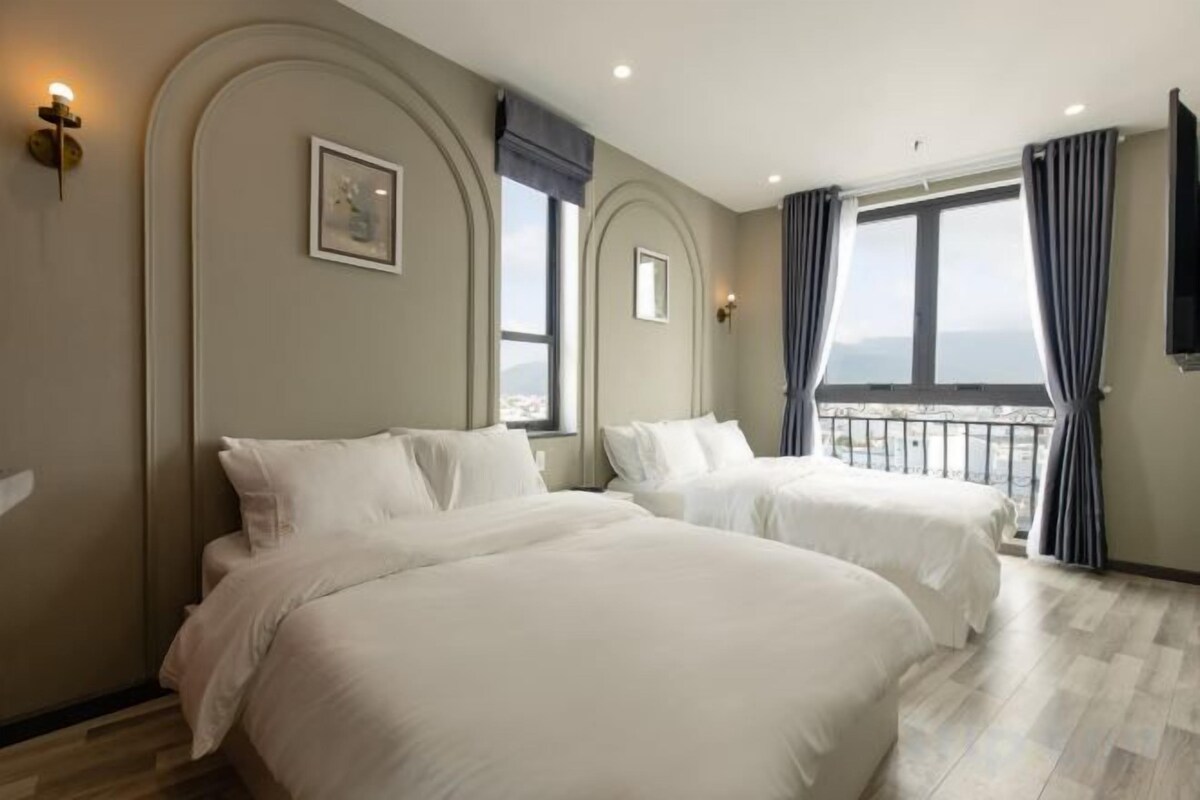 A hotel room with two beds, a balcony, and a view.