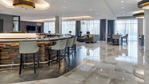 Une cuisine moderne dotée d’un îlot central aux lignes courbes, de tabourets de bar et d’une grande fenêtre.
