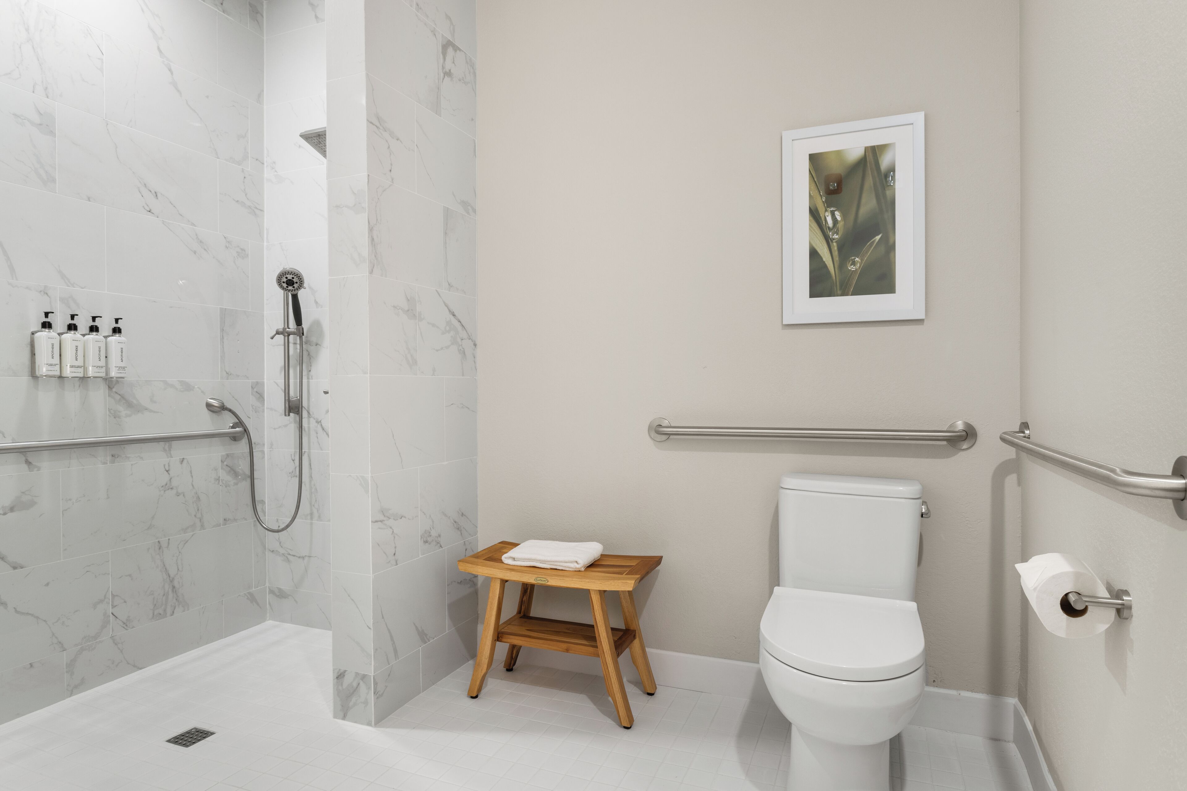 A modern bathroom with a shower, toilet, and a small wooden stool.