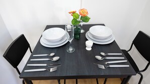 A dining table set with plates, cutlery, and a vase with flowers.
