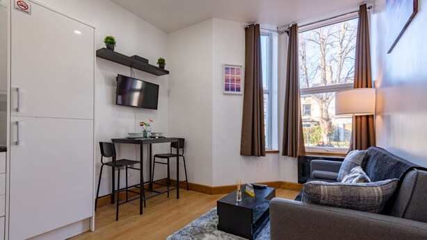 A compact living space with a kitchenette, a dining area, and a seating area with a sofa and a table.