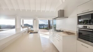Une cuisine moderne dotée d’un grand îlot central, d’un four Bosch et offrant une vue sur les montagnes.