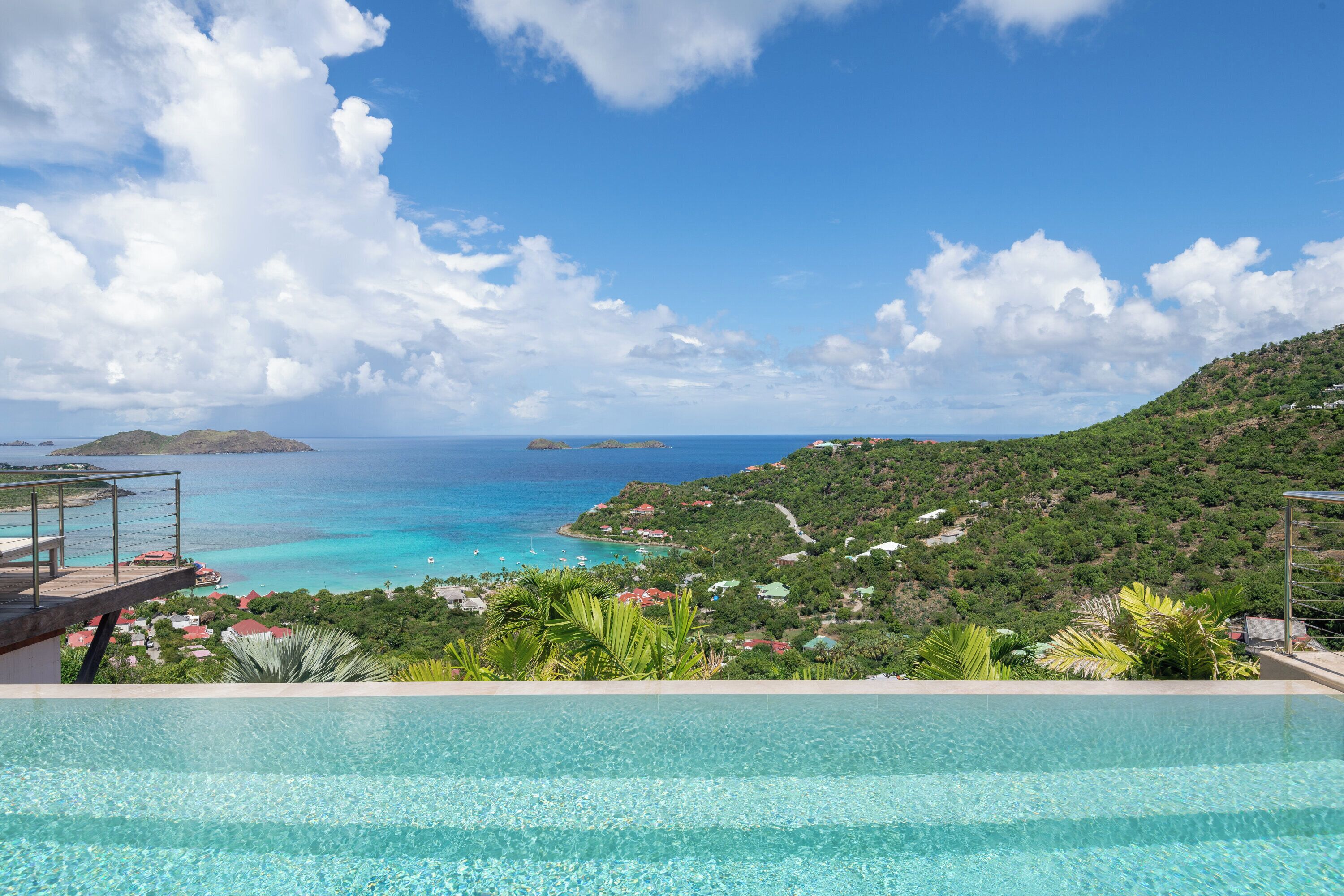 Blick auf ein Schwimmbad mit tropischer Landschaft und entfernten Inseln.