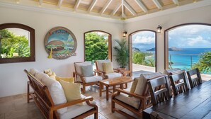 Una habitación soleada con muebles de madera, una mesa grande y vista al océano.