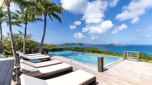 A poolside area with lounge chairs and a view of the ocean.