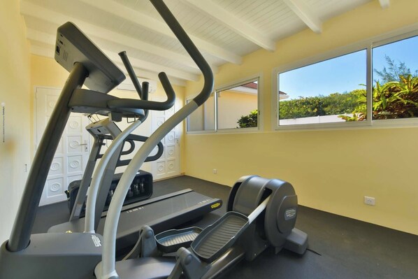 Un gimnasio con cinta de correr, elíptica y escaladora.