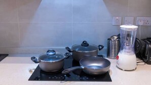 A kitchen with a stove, pots, a pan, a blender, and a kettle. - Plush Studio @Embassy Gardens (Accra)
