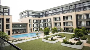 A modern apartment complex with multiple balconies, a swimming pool, and landscaped garden areas. - Plush Studio @Embassy Gardens (Accra)