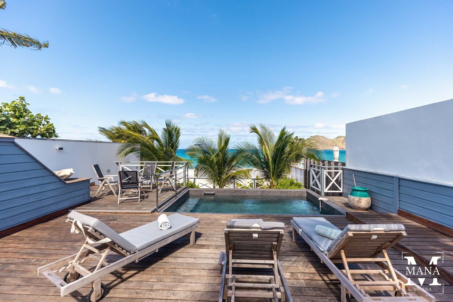 Un espace piscine aménagé sur le toit, avec des chaises longues et une vue sur l’océan.