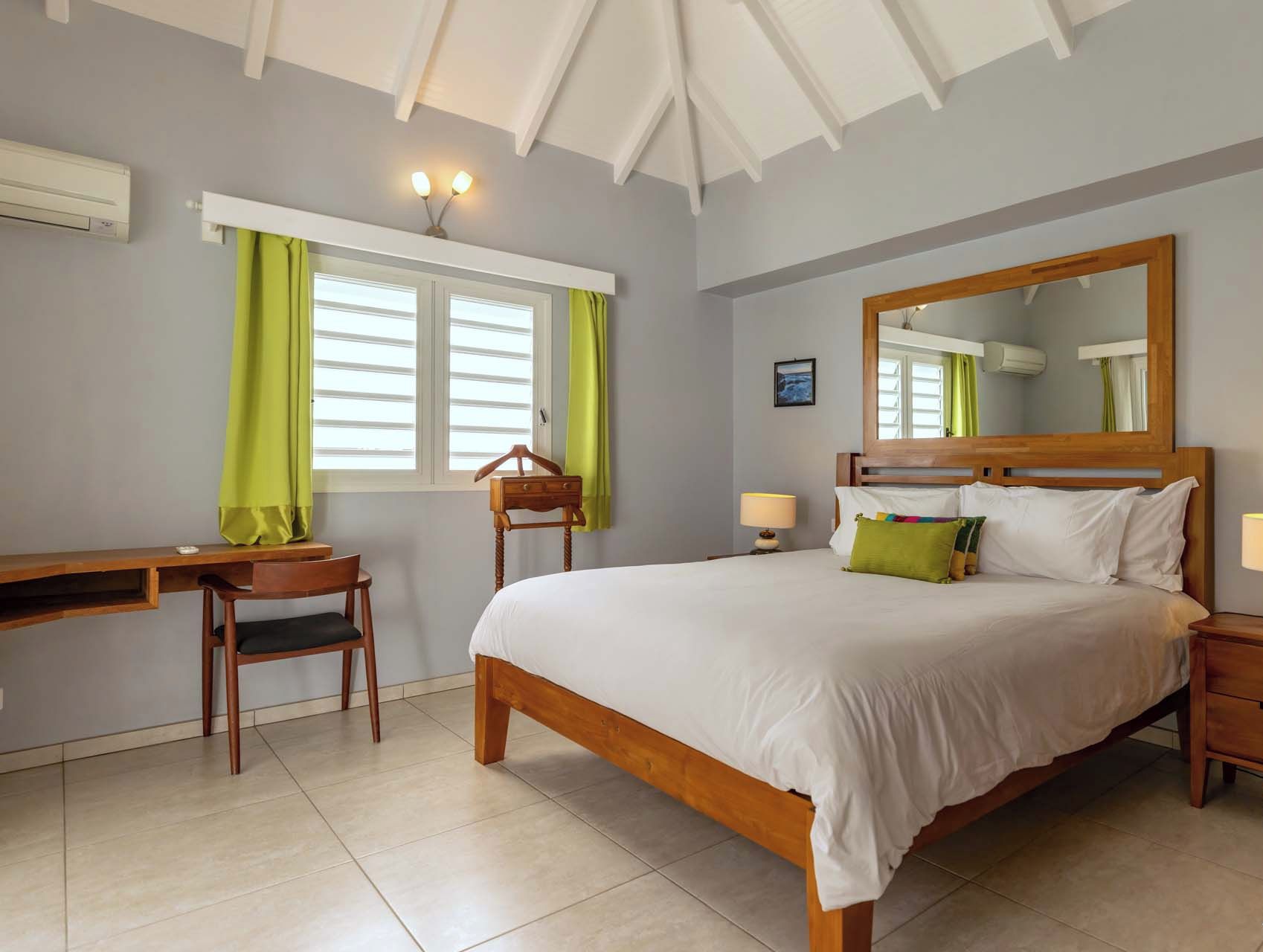 A bedroom with a bed, bedside tables, a desk, and a chair.