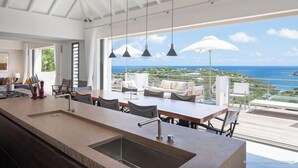Una cocina moderna con una isla grande, comedor y vista al océano.
