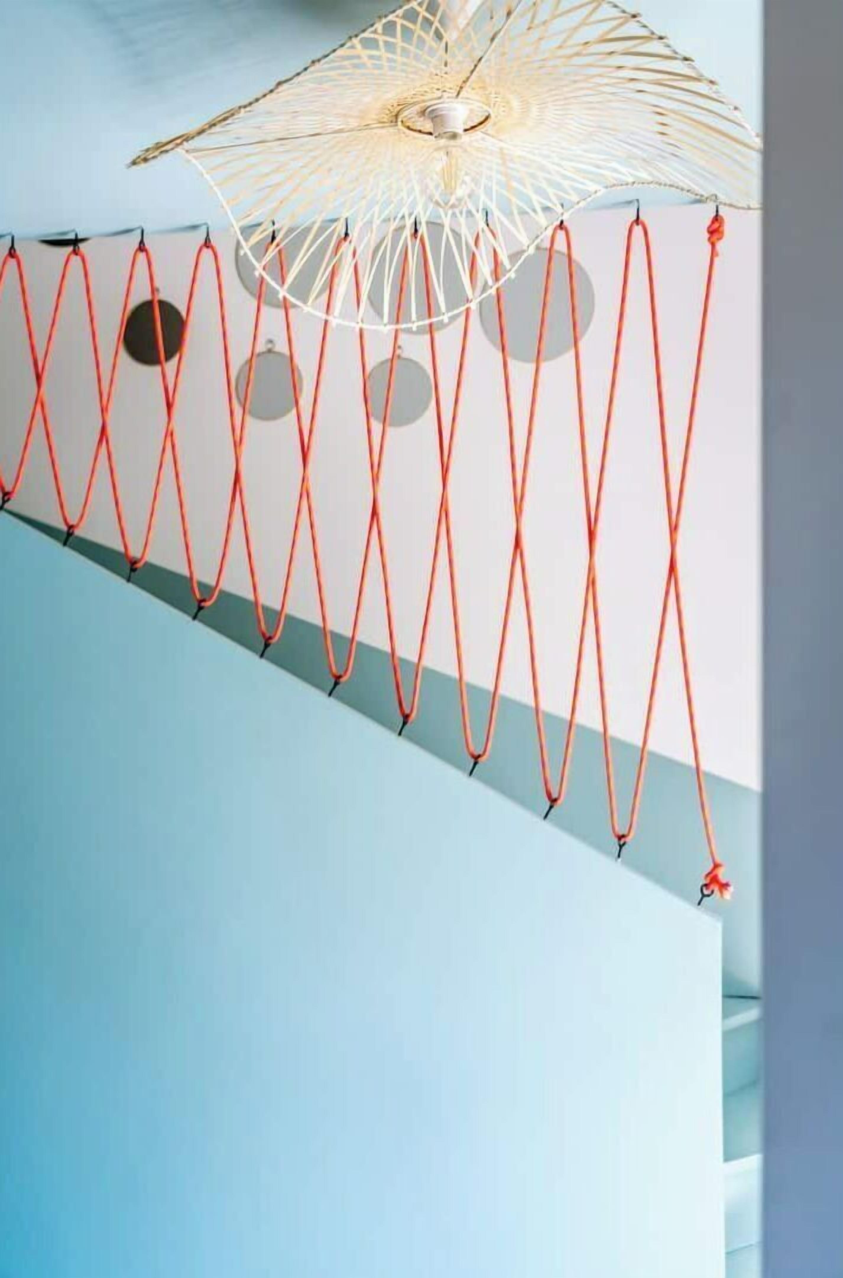 Techo con lámpara de diseño geométrico y cuerdas rojas.