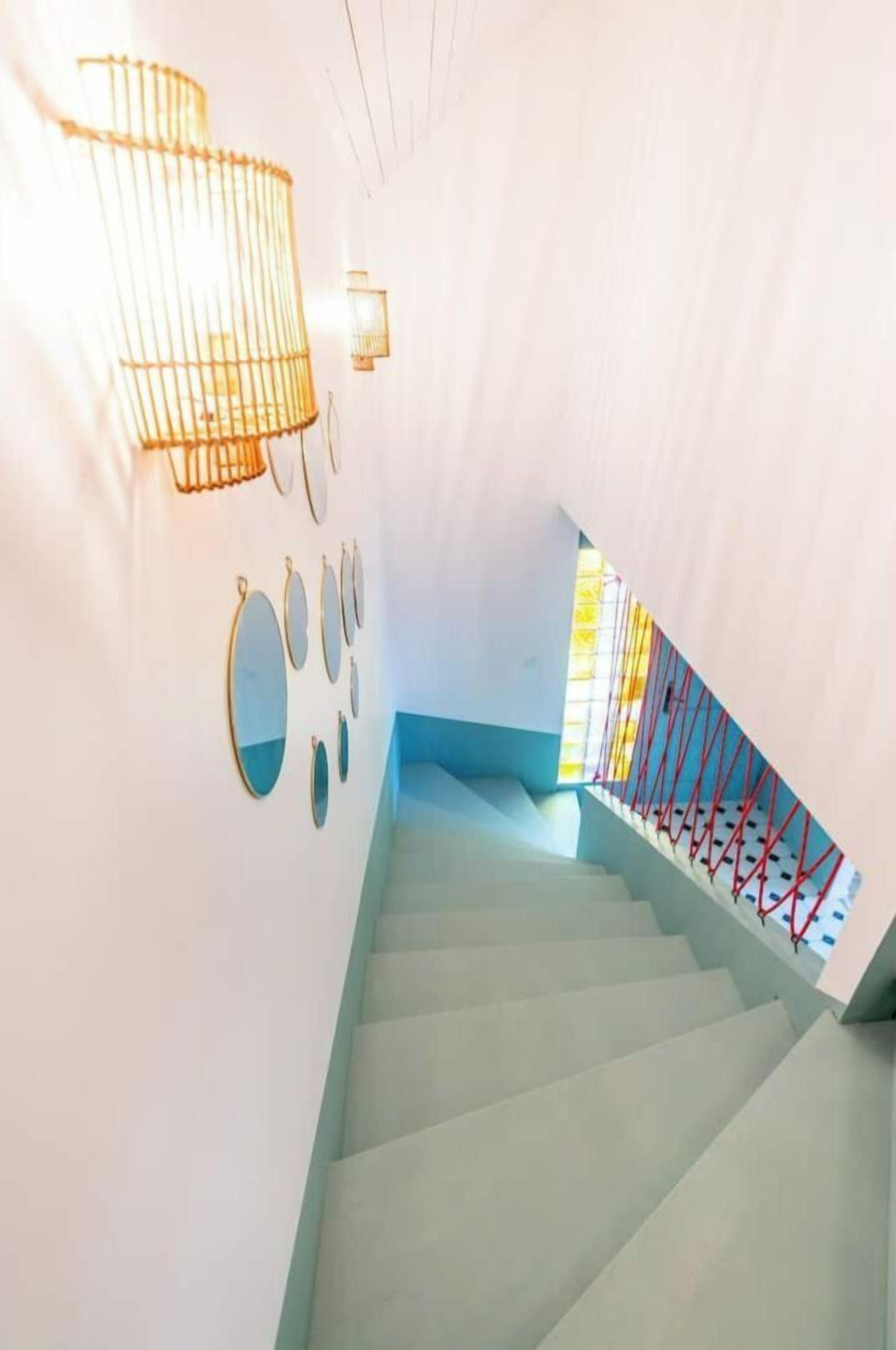 A staircase with a light blue wall and a red railing.