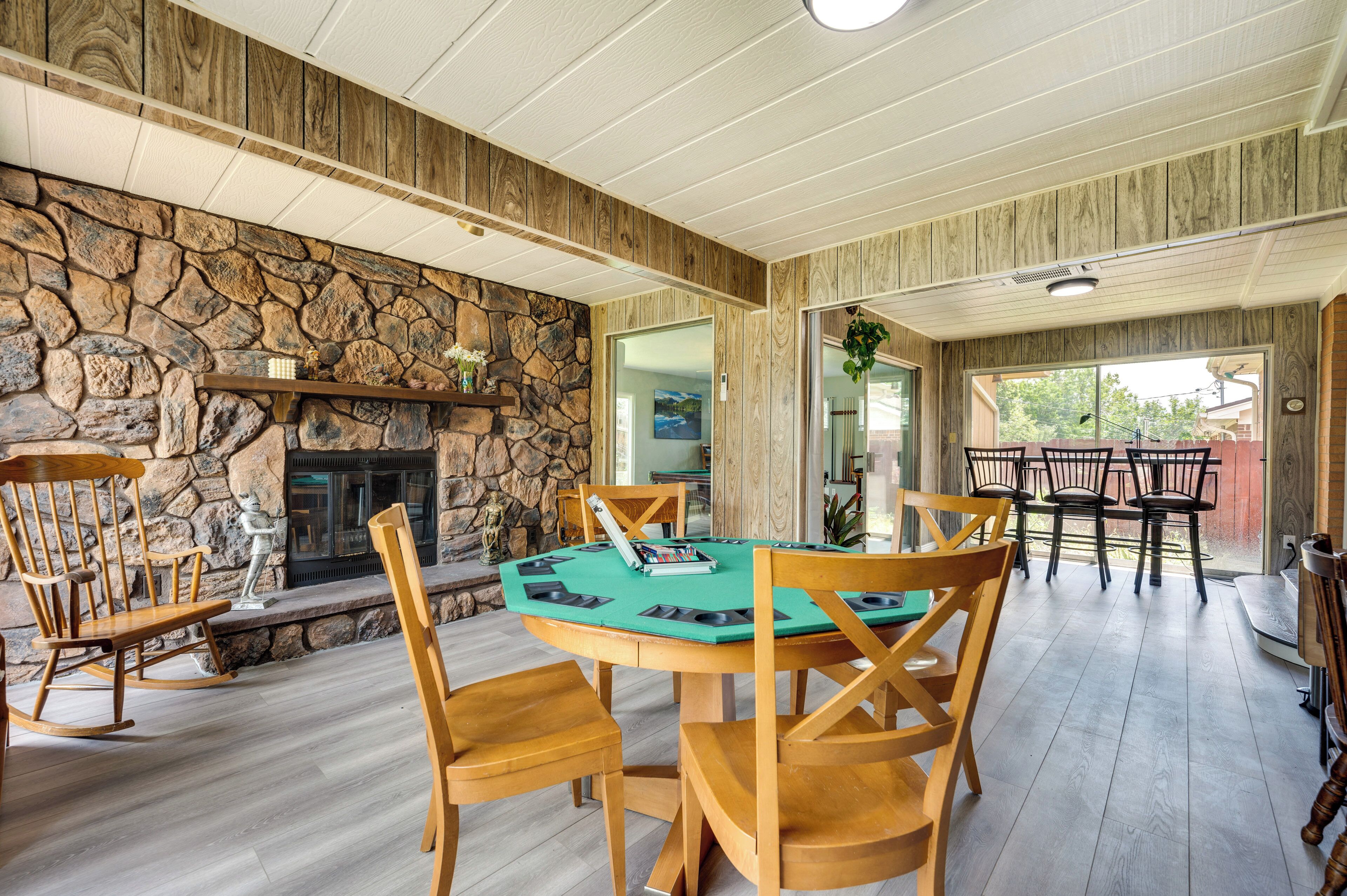 A cozy room with a stone fireplace, wooden chairs, and a green poker table.