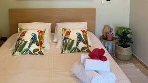A hotel room with a bed, pillows, a Buddha painting, a ceiling light, and a small side table with a plant. - Lexotique Cottage (Solliès-Pont)