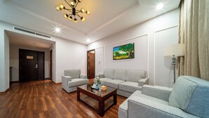 Una sala de estar moderna con piso de madera, una mesa de centro de vidrio, sofás grises y un cuadro en la pared.
