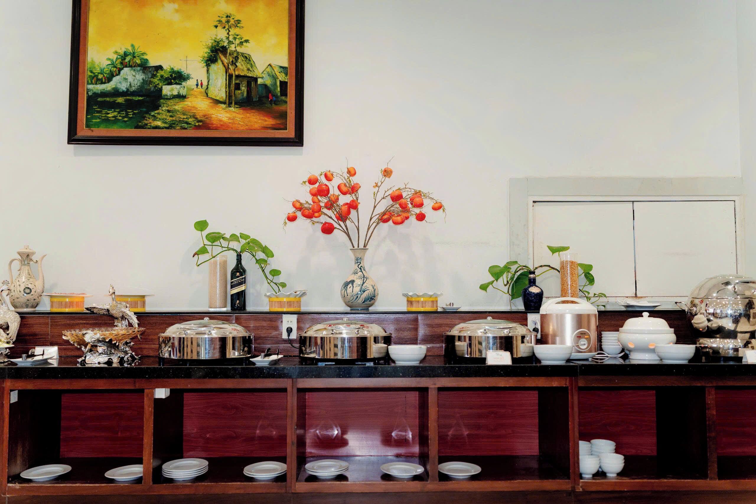 A kitchen with a painting, a vase with red flowers, and various kitchenware.