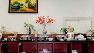 A kitchen with a painting, a vase with red flowers, and various kitchenware.