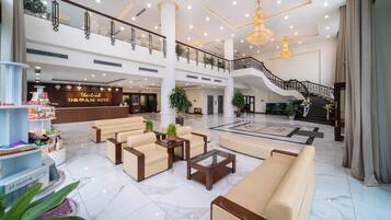 A spacious lobby with a reception desk, seating area, and a staircase leading to an upper level.