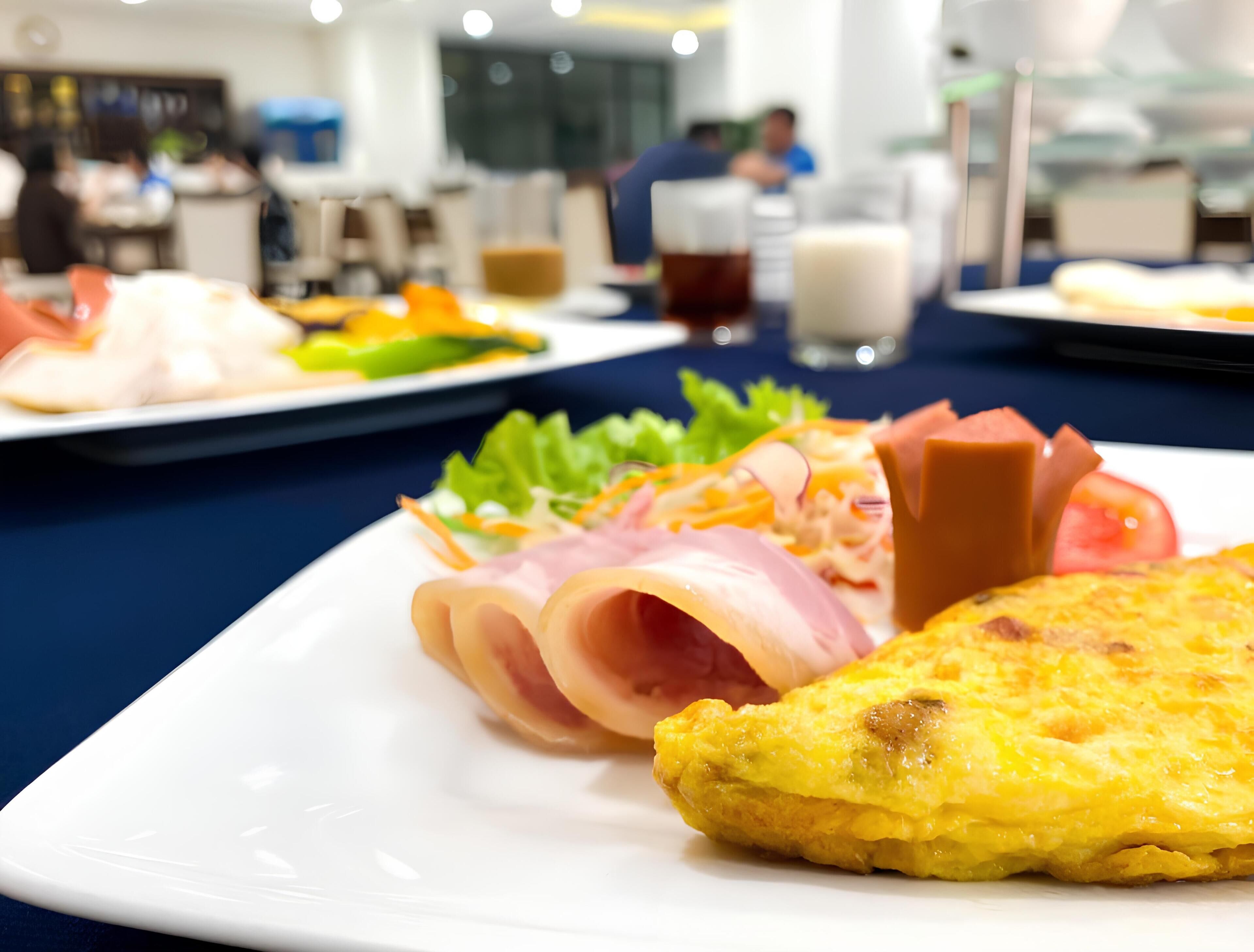 A dining table with various dishes including a plate with sliced ham, a salad, and a piece of omelette.