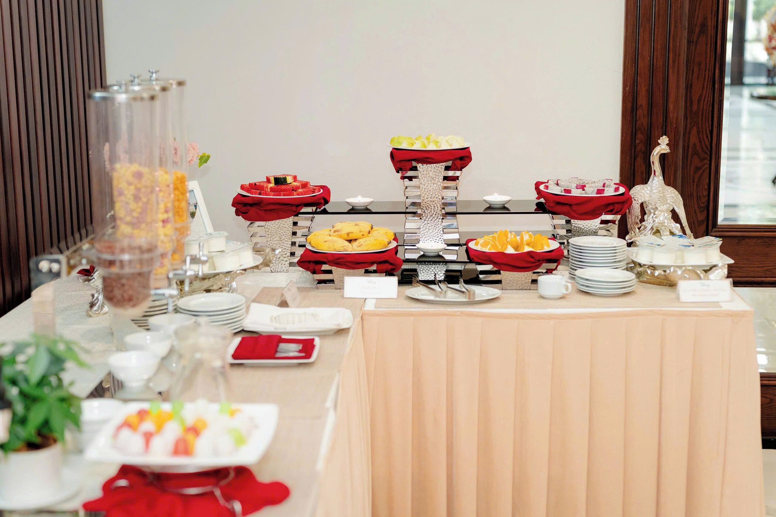A buffet table with various food items and a decorative silver statue.