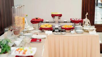 A buffet table with various food items and a decorative silver statue.