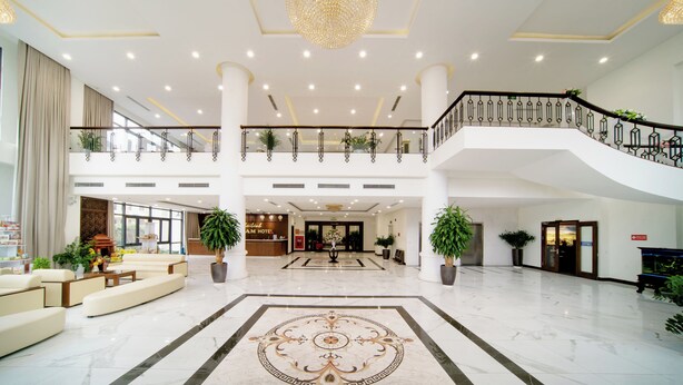 Un hall amplio con una imponente lámpara de araña, una recepción y una escalera que sube a un nivel superior.