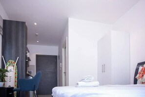 A modern hotel room with a bed, a desk, a chair, and a wardrobe. - Beautiful Suite @Embassy Gardens (Accra)