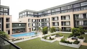 A modern apartment complex with multiple balconies, a swimming pool, and landscaped garden areas. - Beautiful Suite @Embassy Gardens (Accra)