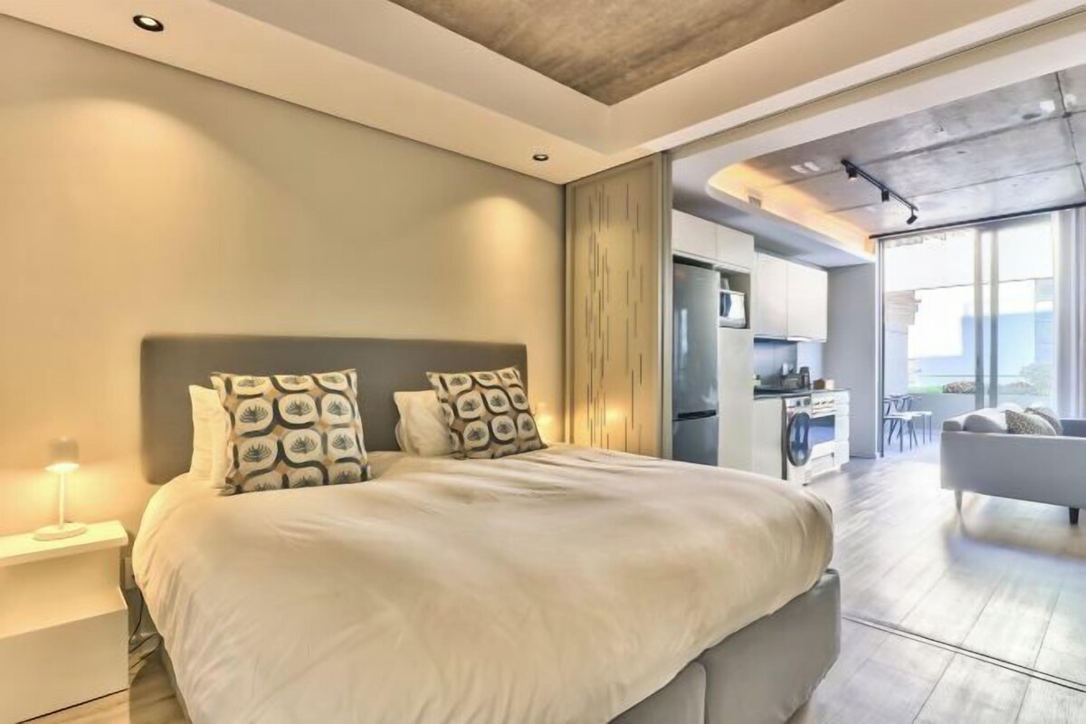 A modern bedroom with a large bed, a nightstand, and a built-in wardrobe.