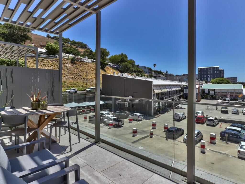A view from a balcony overlooking a parking lot with cars and a building in the background.