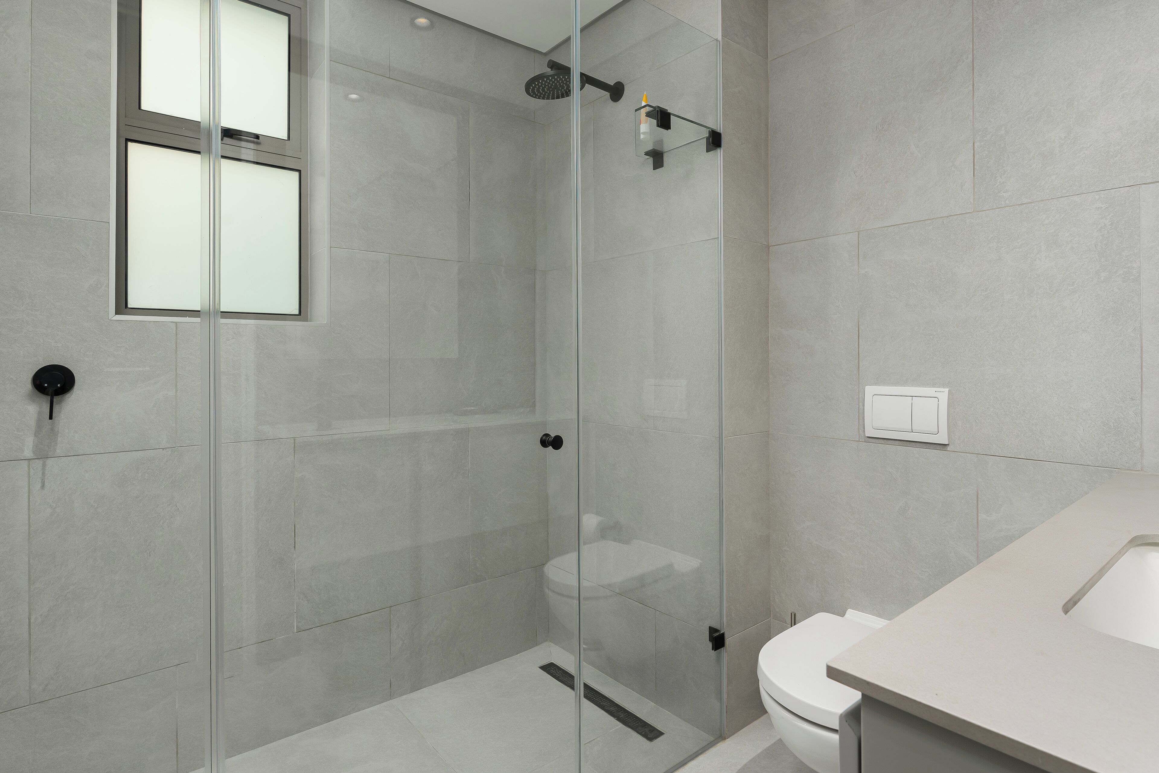 Un baño moderno con cabina de ducha de vidrio, inodoro y lavamanos.