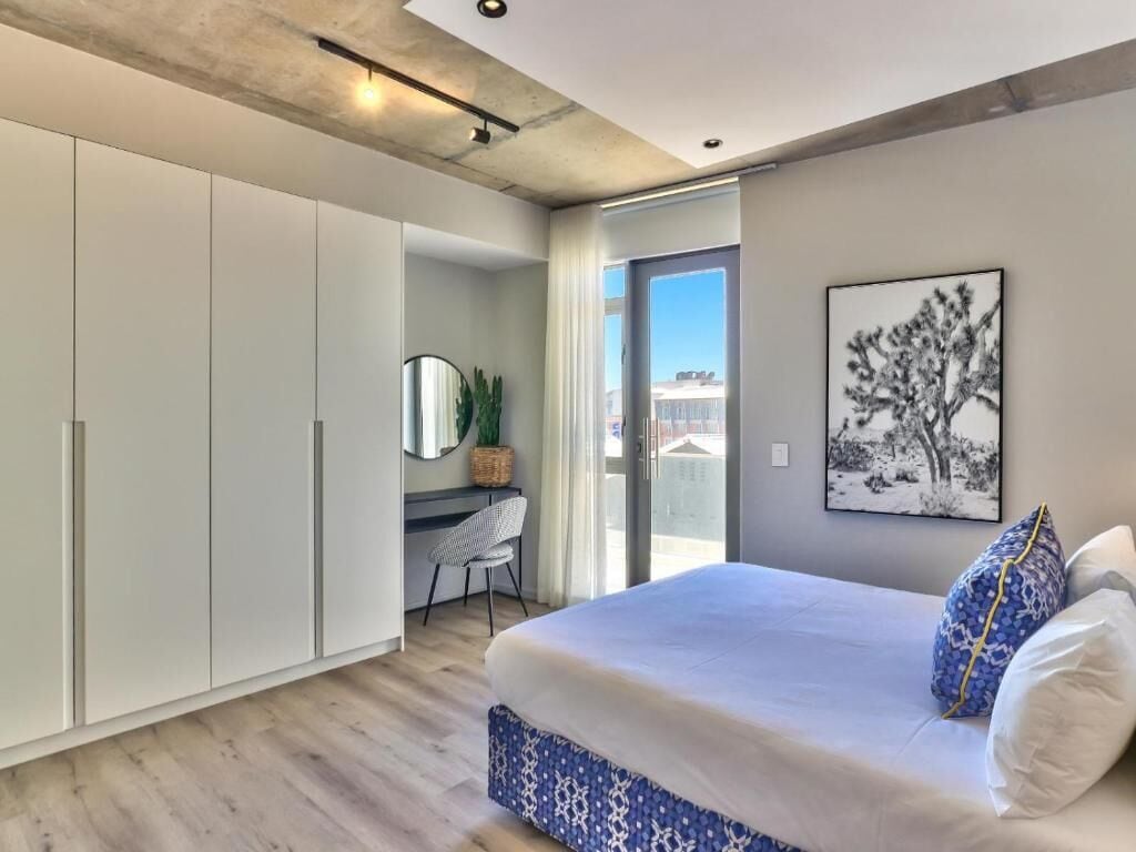 Een moderne slaapkamer met een groot bed, een bureau en een kledingkast.