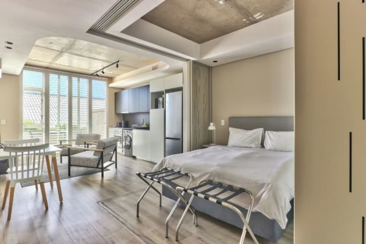 A modern hotel room with a bed, a desk, and a chair.