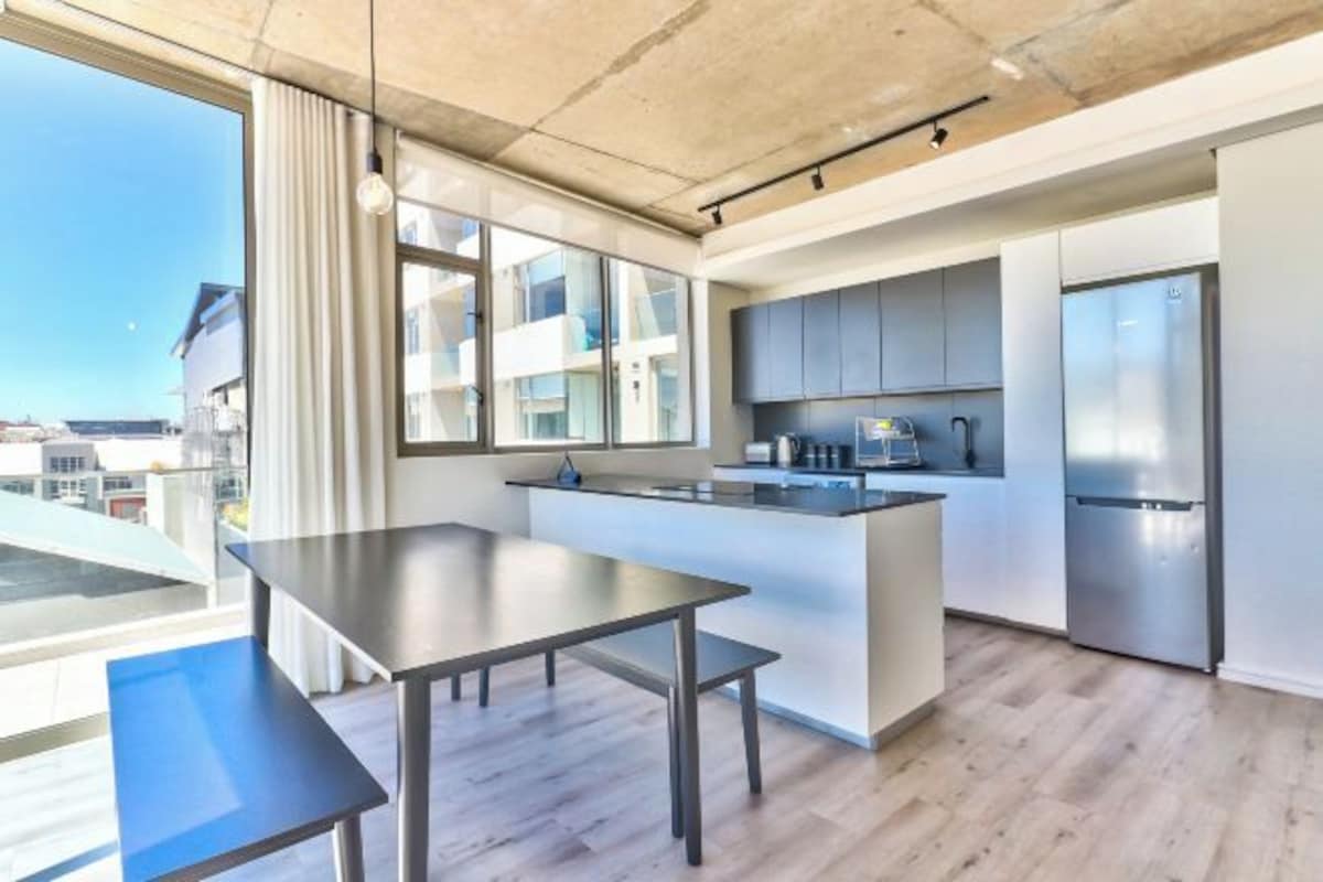 A modern kitchen with a large island, stainless steel appliances, and a view of the city.