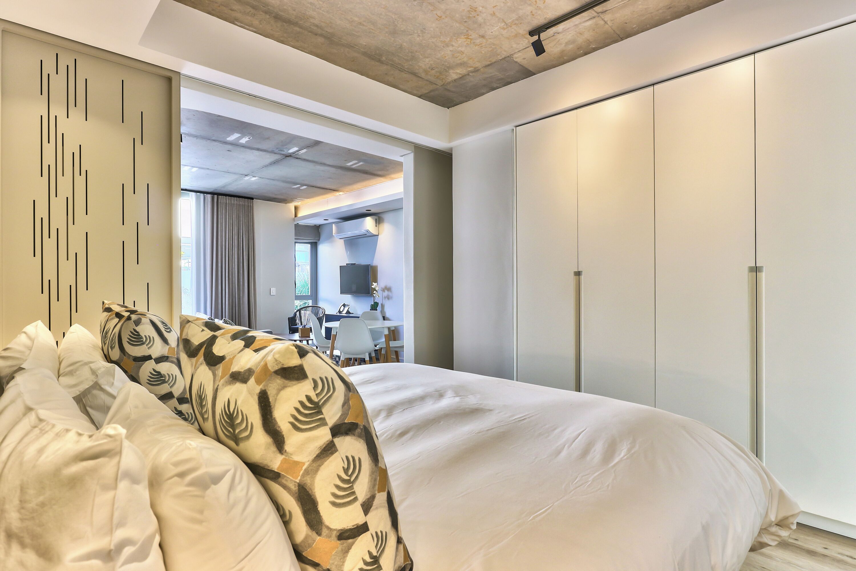 Une chambre d’hôtel moderne avec un grand lit, une armoire et une vue sur la salle à manger.