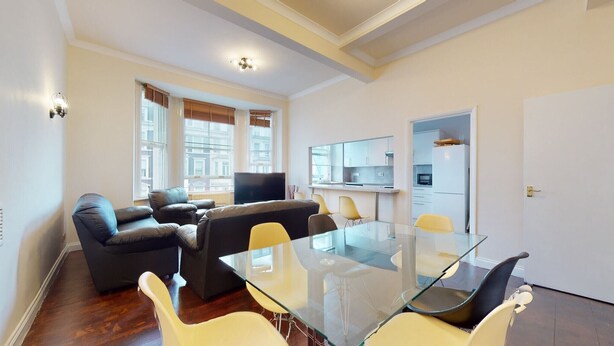 Un appartement moderne doté d’une table à manger en verre, de canapés en cuir et d’un coin cuisine.