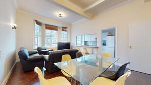 Un apartamento moderno con una mesa de comedor de vidrio, sofás de cuero y una zona de cocina.