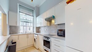 Une cuisine moderne avec des meubles blancs, un four encastré, un micro-ondes et un réfrigérateur Siemens.