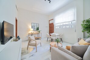 A modern living room with a flat-screen TV, a dining area with a table and chairs, and a large window with a view. - iloftmalaga Carreteria 77 - II (Malaga)
