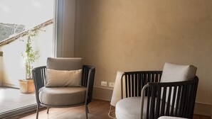 Et værelse med trægulv, to stole, et vindue og et bjælkekonstrueret loft.