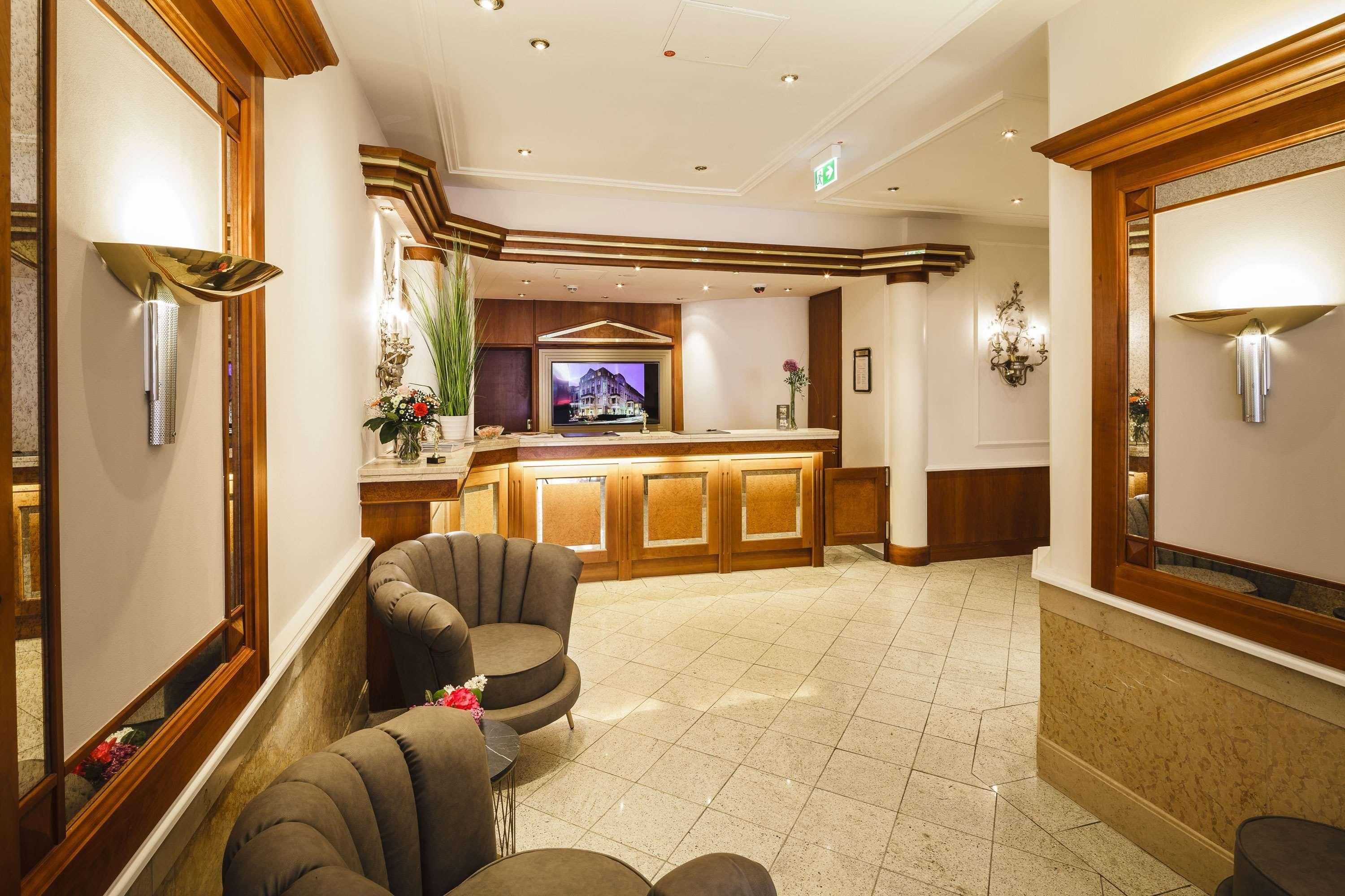A lobby with a reception desk, seating area, and a television screen.