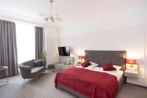 A modern hotel room with a large bed, a TV, a desk, and a chair. - TOP Hotel Hansa Wiesbaden (Wiesbaden)