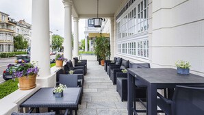 Un espace extérieur aménagé avec des tables et des chaises, des plantes en pot et une vue sur la rue.