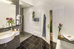 Un baño moderno con un lavamanos grande, una ducha y un perchero blanco.