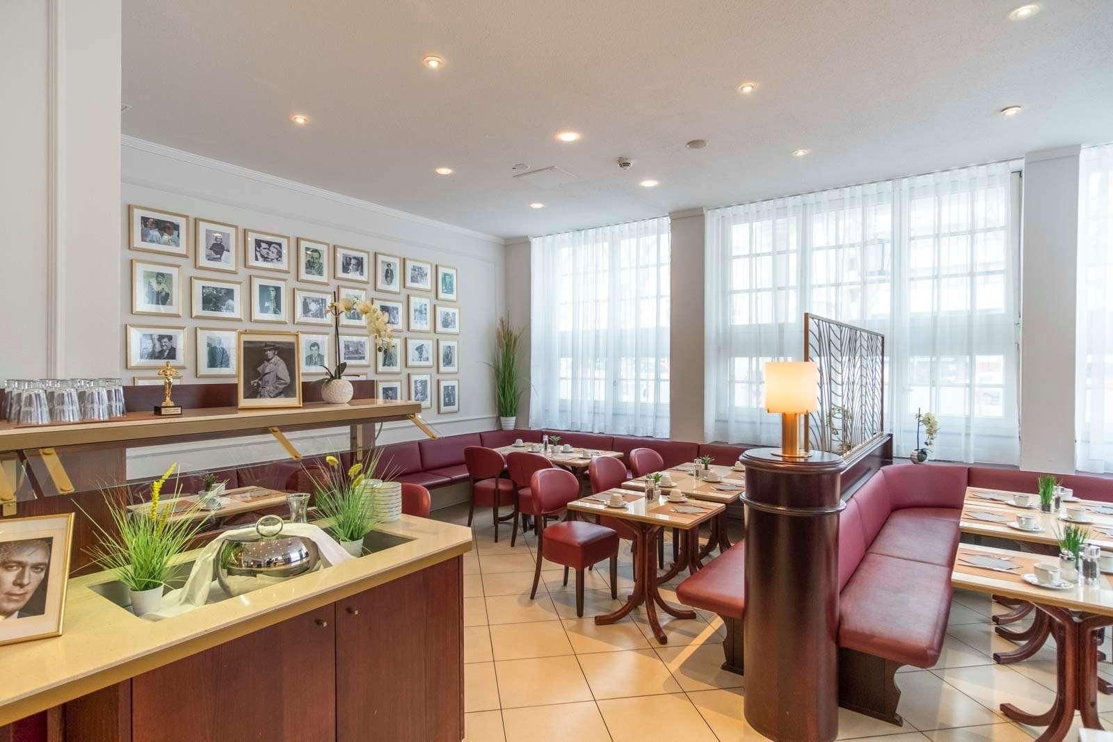 A restaurant with a long counter, multiple seating areas, and framed pictures on the wall.