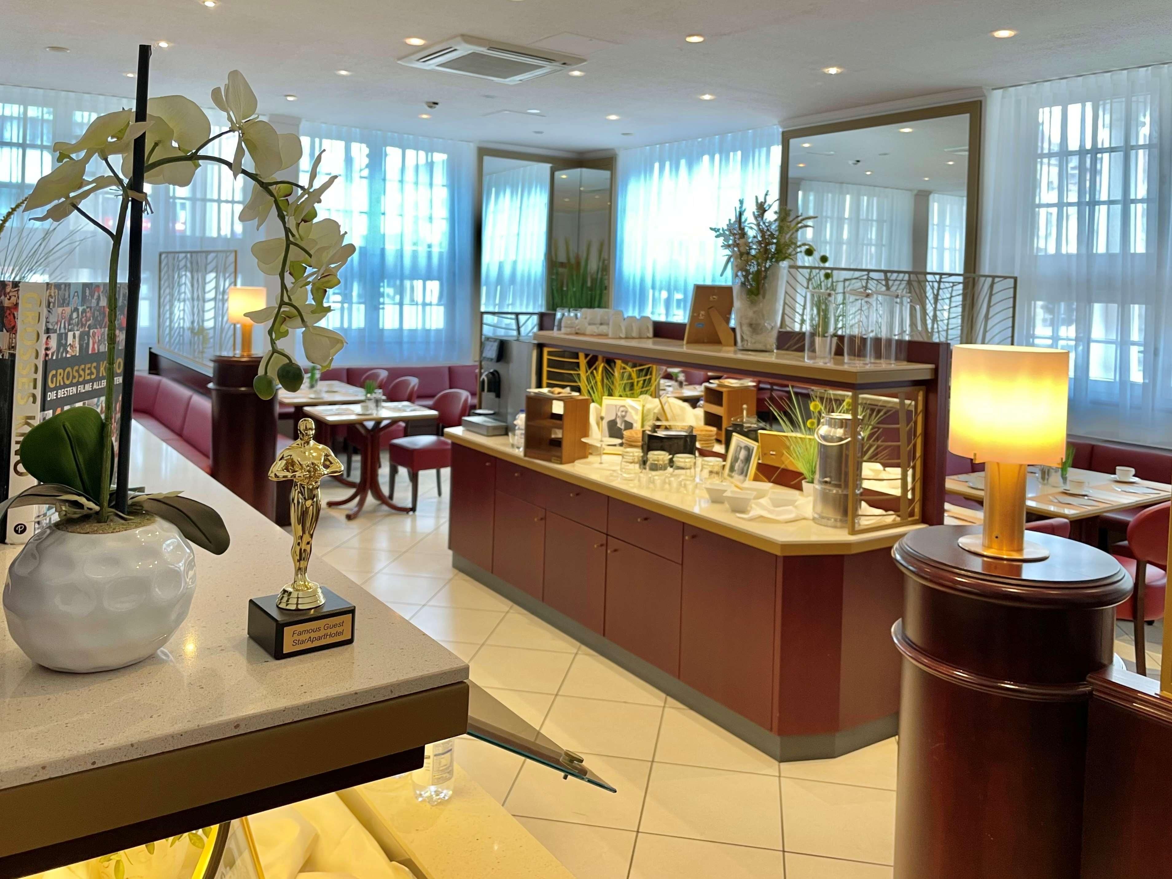 A hotel lobby with a reception desk, a seating area with sofas, and a dining area.