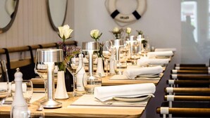 Un espace repas avec des tables dressées pour le service, agrémenté de nappes blanches, de couverts en argent et de verres.