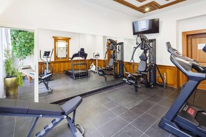 Ein Fitnessraum mit Trainingsgeräten, Laufband und Spiegel.